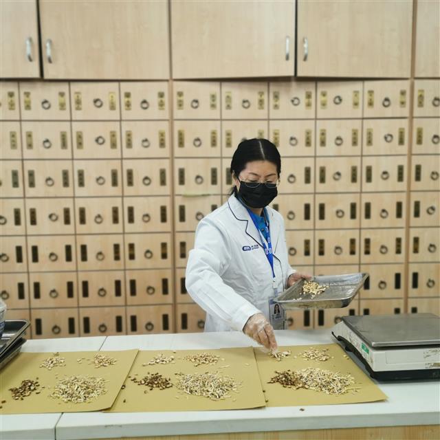 　侯惠鳴為顧客抓藥。